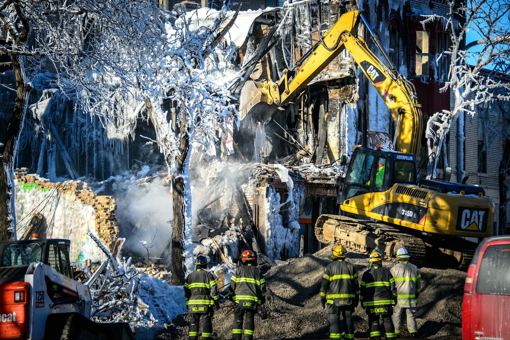 Investigators brought in a backhoe Thursday, Jan. 2, 2013, to knock down unstable walls in order to search for victims at the scene of Wednesday's fire on Cedar Ave near 6th Ave in Minneapolis.