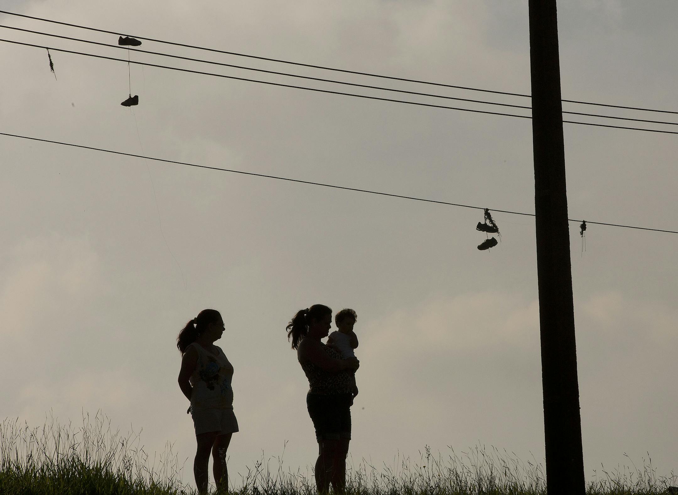 Two women watch Volkswagen workers protest against the layoff of 800 employees, next to the company's plant in Sao Bernardo do Campo, Brazil, Monday, Jan. 12, 2015. Volkswagen said in a recent statement that the company needs to reduce costs at its local factory. Workers there have been striking since Tuesday, halting production at the factory. (AP Photo/Andre Penner)