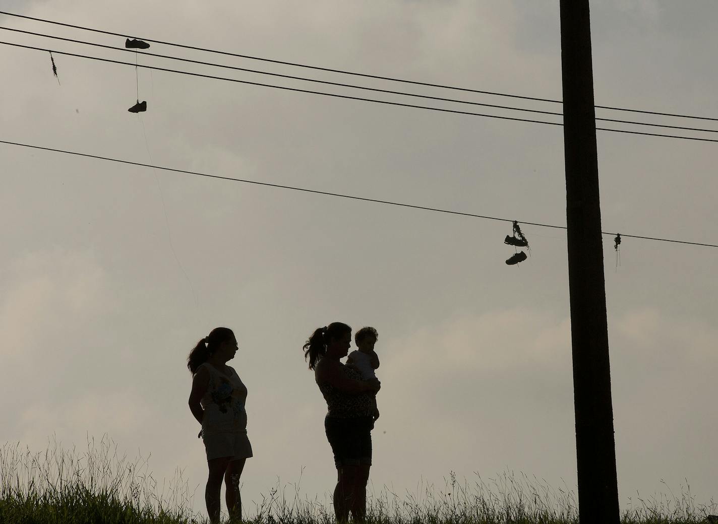 Two women watch Volkswagen workers protest against the layoff of 800 employees, next to the company's plant in Sao Bernardo do Campo, Brazil, Monday, Jan. 12, 2015. Volkswagen said in a recent statement that the company needs to reduce costs at its local factory. Workers there have been striking since Tuesday, halting production at the factory. (AP Photo/Andre Penner)