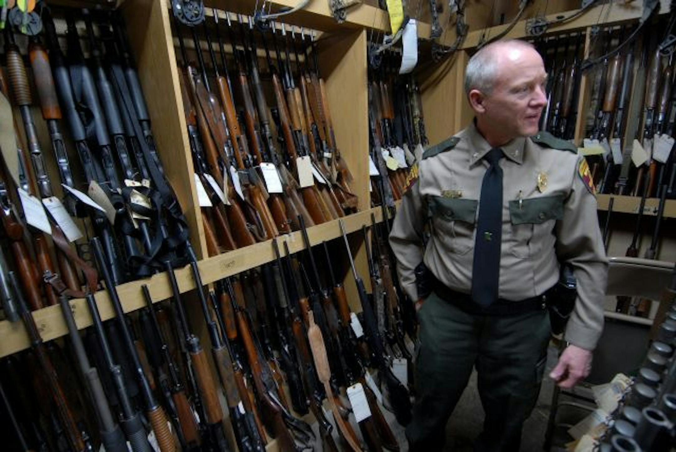 Jim Konrad, DNR chief of enforcement stood with some of the hundreds of guns to be auctioned. The DNR has been stockpiling guns its conservation officers have seized from hunters violating laws over the past few years, and now the agency's storeroom is filled with more than 200 guns, mostly shotguns and rifles.