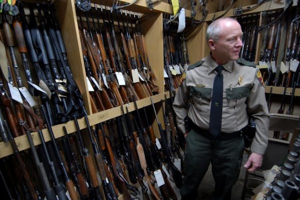 Jim Konrad, DNR chief of enforcement stood with some of the hundreds of guns to be auctioned. The DNR has been stockpiling guns its conservation offic