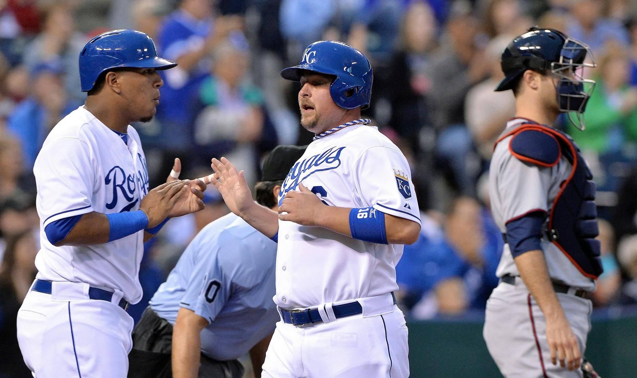 Kansas City Royals' Salvador Perez (13) and Billy Butler (16) greet each other behind Minnesota Twins catcher Joe Mauer (7) after both scored on a double by David Lough in the first inning
