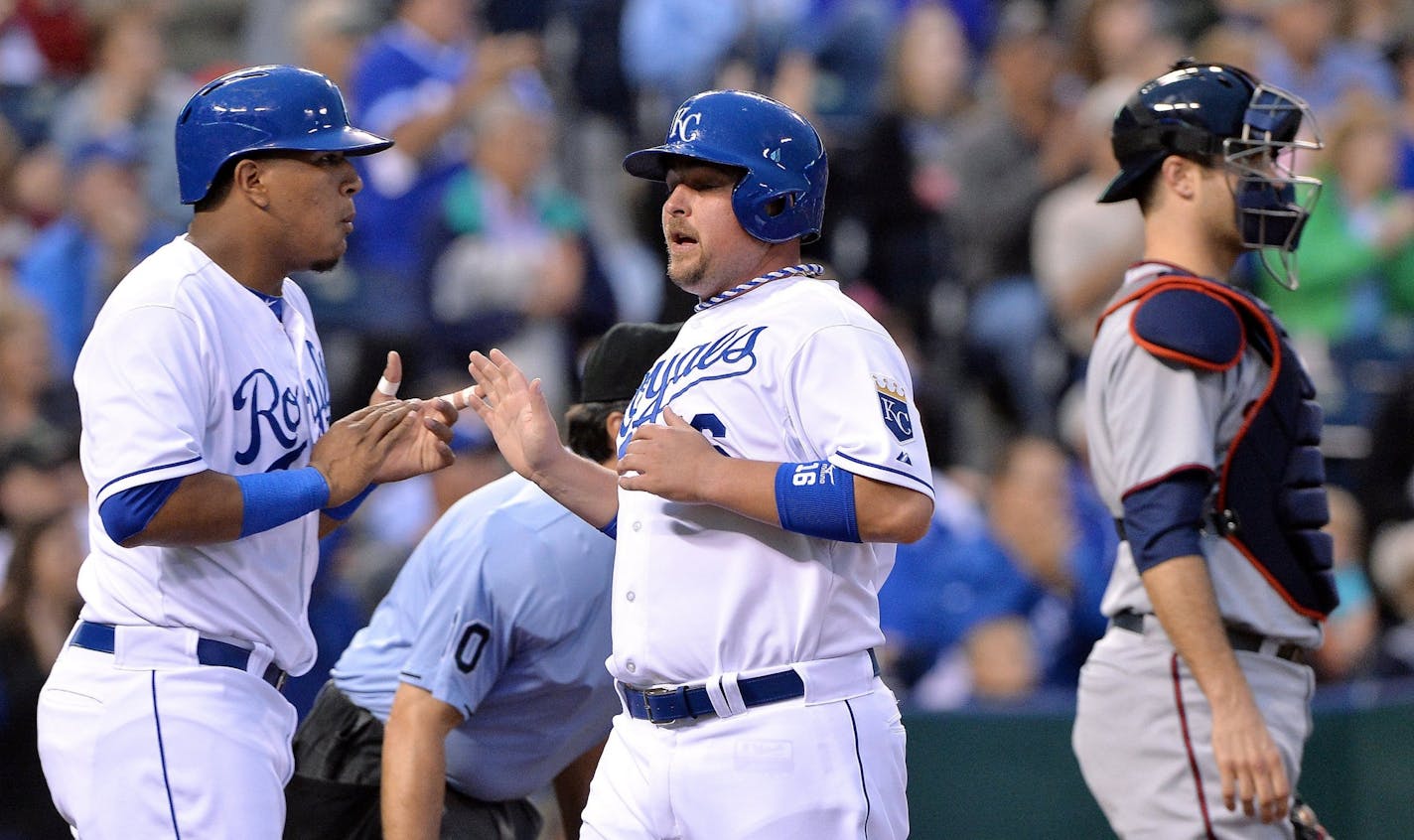 Kansas City Royals' Salvador Perez (13) and Billy Butler (16) greet each other behind Minnesota Twins catcher Joe Mauer (7) after both scored on a double by David Lough in the first inning