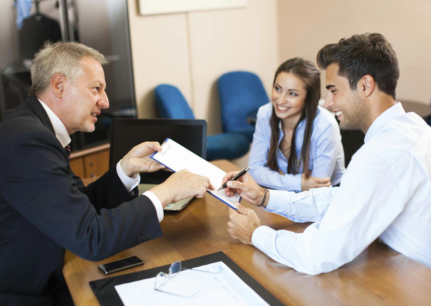 Senior businessman showing a document to sign to a couple