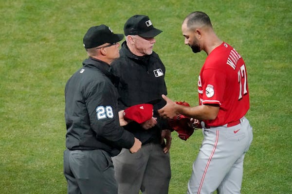 Cincinnati Reds' relief pitcher Art Warren (77) gets a glove and cap check for sticky substances from umpires, including second base umpire Jim Wolf, 