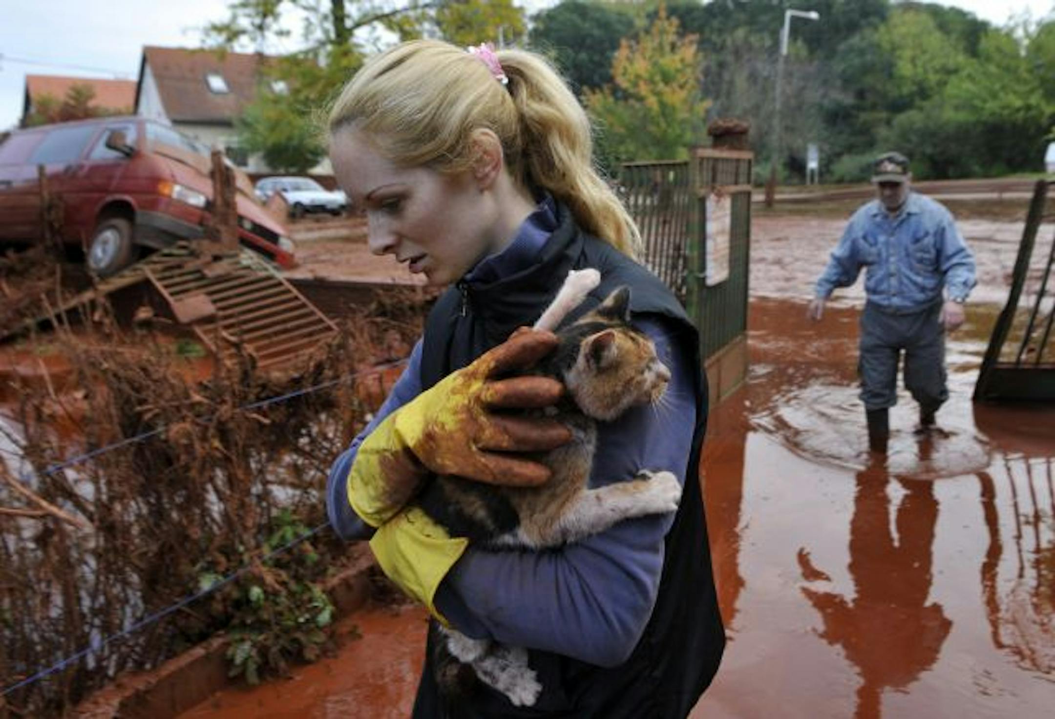 In the sludge-filled town of Devecser, Hungary, Tunde Erdelyi held her cat out of harm's way as Janos Kis waded through his yard.
