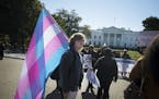A protester carries a transgender flag outside of the White House in Washington, Oct. 22, 2018. Activists in the LGBT community mobilized a fast and f