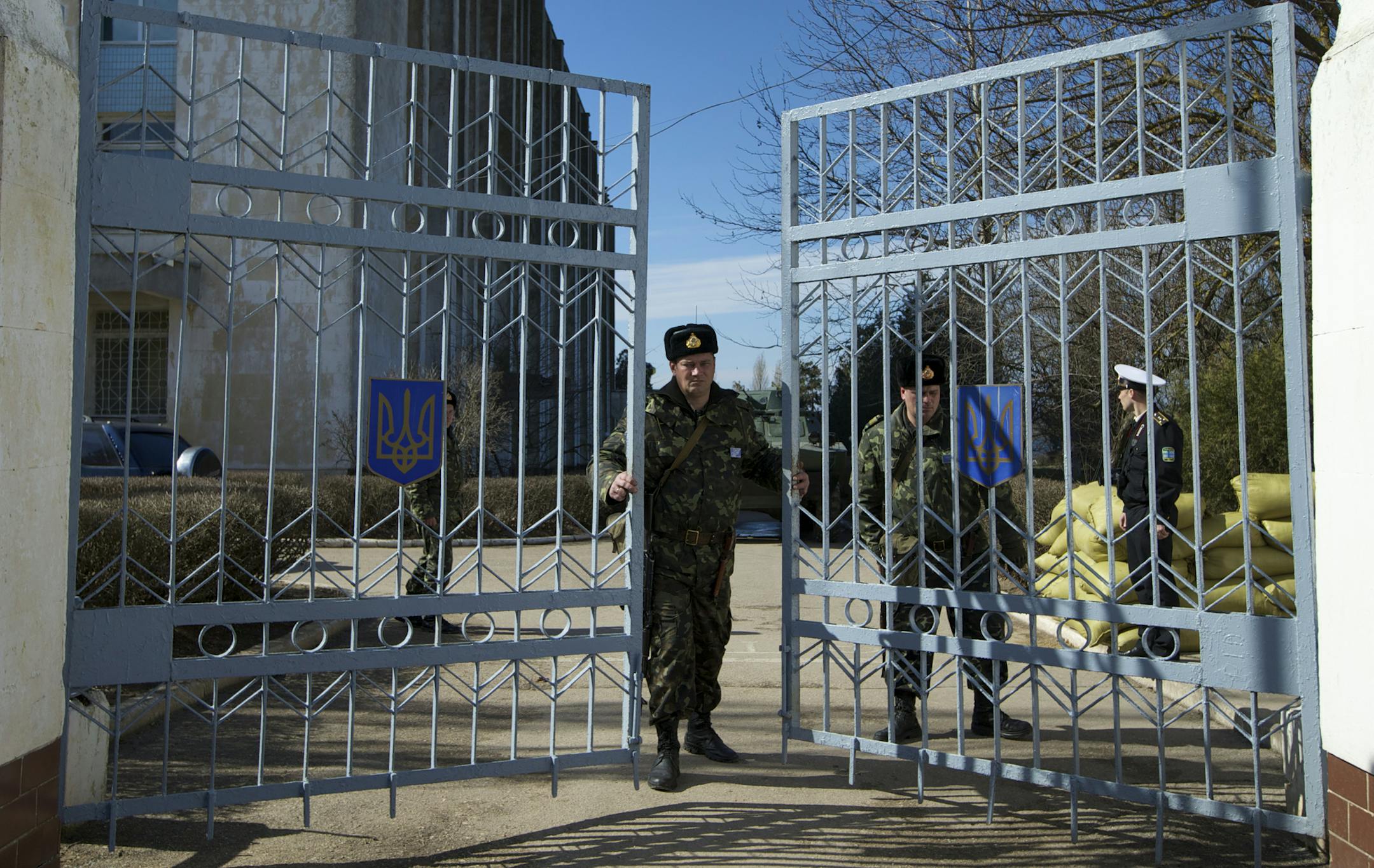 A Ukrainian soldier closes the naval base headquarter gate in the town of Novo-Ozerne, some 90 km west of the Crimean capital Simferopol, Ukraine, on Monday March 3, 2014. For years, the little Crimean town was closed off from the rest of the world, a secretive community, at the edge of a key Soviet naval base, sealed by roadblocks and armed guards. Thereís not much in town anymore. But the Russians want it. And the little forgotten town is now sharply divided, torn between those who welcom
