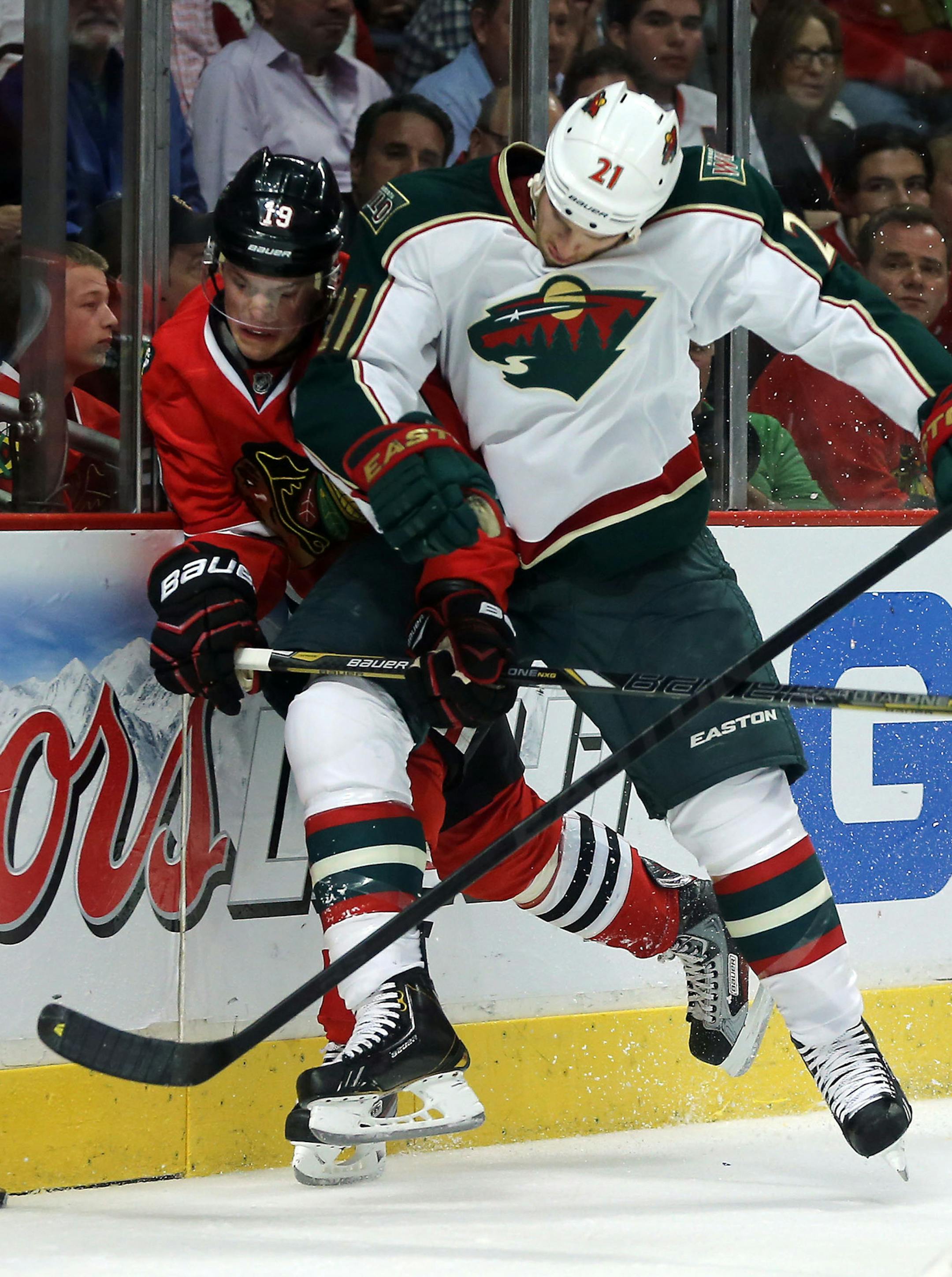 The Blackhawks' Jonathan Toews, left, was driven into the boards by the Wild's Kyle Brodziak in the second period of Game 1 of the Western Conference first-round playoff series at United Center in Chicago.