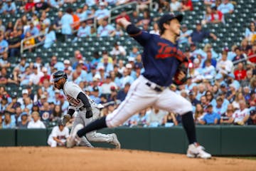 Akil Baddoo (60), Tigers, left, tries to steal second base as Kenta Maeda (18), Twins, throws a pitch against the Detroit Tigers.