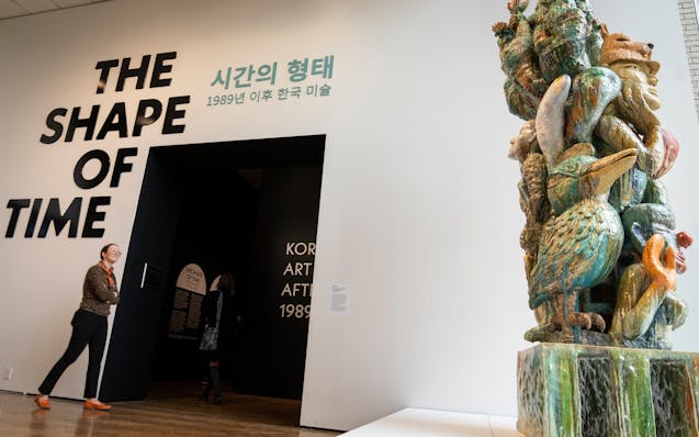 People enter the gallery, walking past “Monument for Parents” by Sunkoo Yuh, at the entrance to “The Shape of Time: Korean Art after 1989” at 