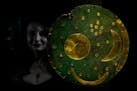A member of staff poses next to the 'Nebra Sky Disc' which dates from around 1600 BCE, and is the oldest surviving representation of the cosmos, on di