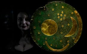 A member of staff poses next to the 'Nebra Sky Disc' which dates from around 1600 BCE, and is the oldest surviving representation of the cosmos, on di