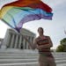 FILE- In this June 26, 2013, file photo, gay rights advocate Vin Testa waves a rainbow flag in front of the Supreme Court in Washington. Thousands of 