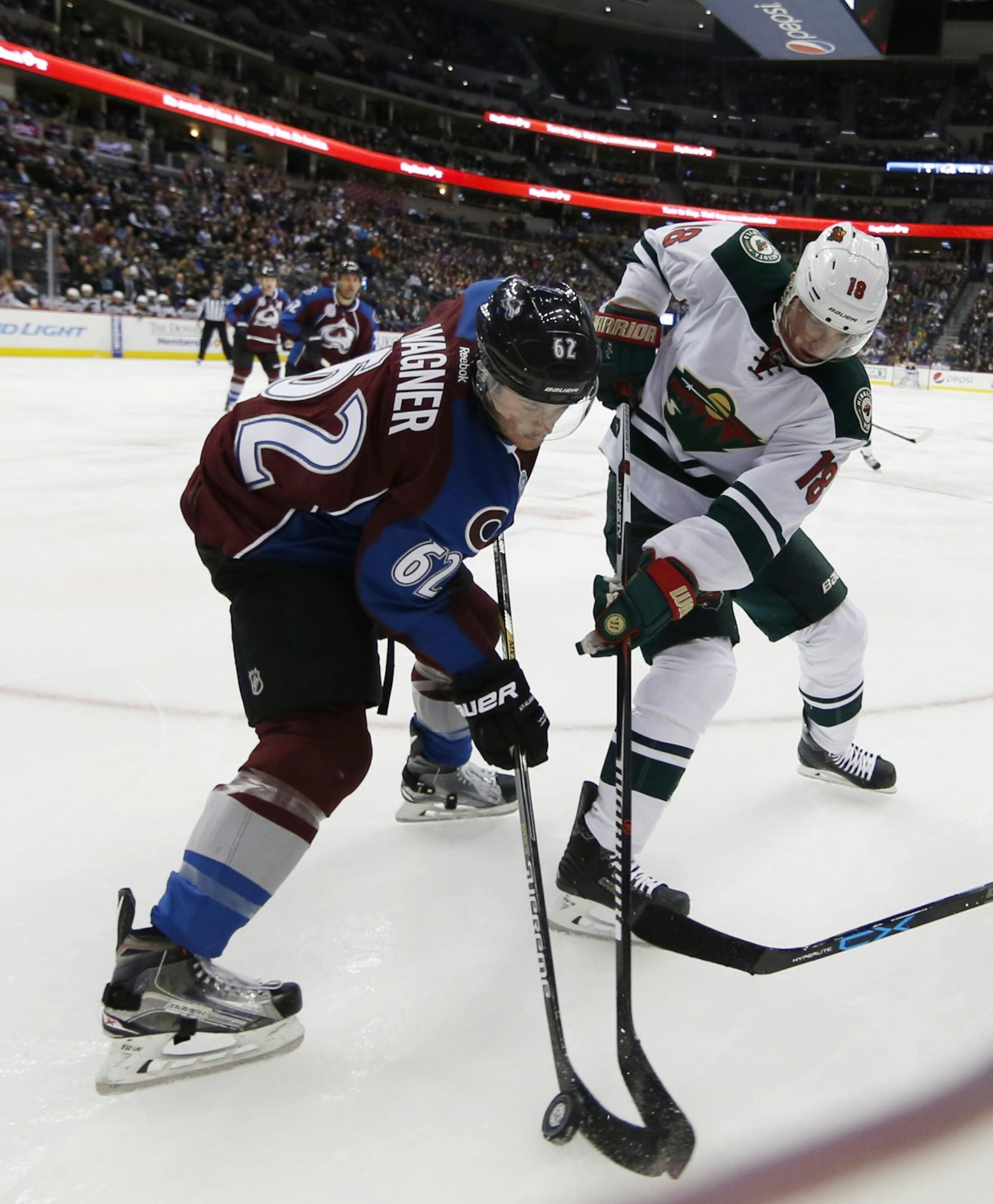 Colorado Avalanche right wing Chris Wagner, left, fights for control of the puck with Minnesota Wild center Ryan Carter in the second period of an NHL hockey game, Monday, Dec. 7, 2015, in Denver.