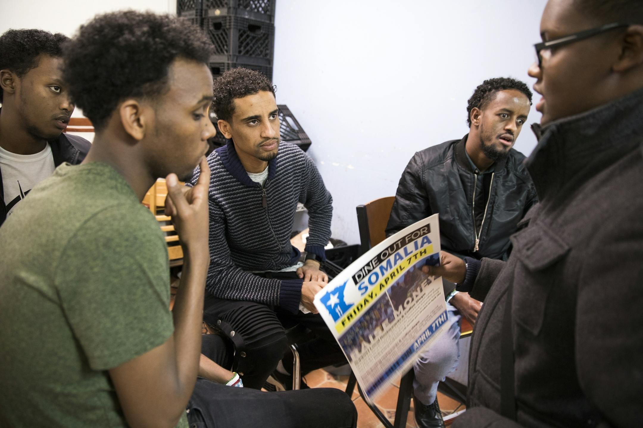 Khalid Mohamed, from right, hands out flyers to Hassan Muse, Feysal Ali, Dayir Ibrahim and Mohammed Sheikh inside Sahan Restaurant to raise awareness for Dine Out for Somalia at the Village Market mall in Minneapolis.