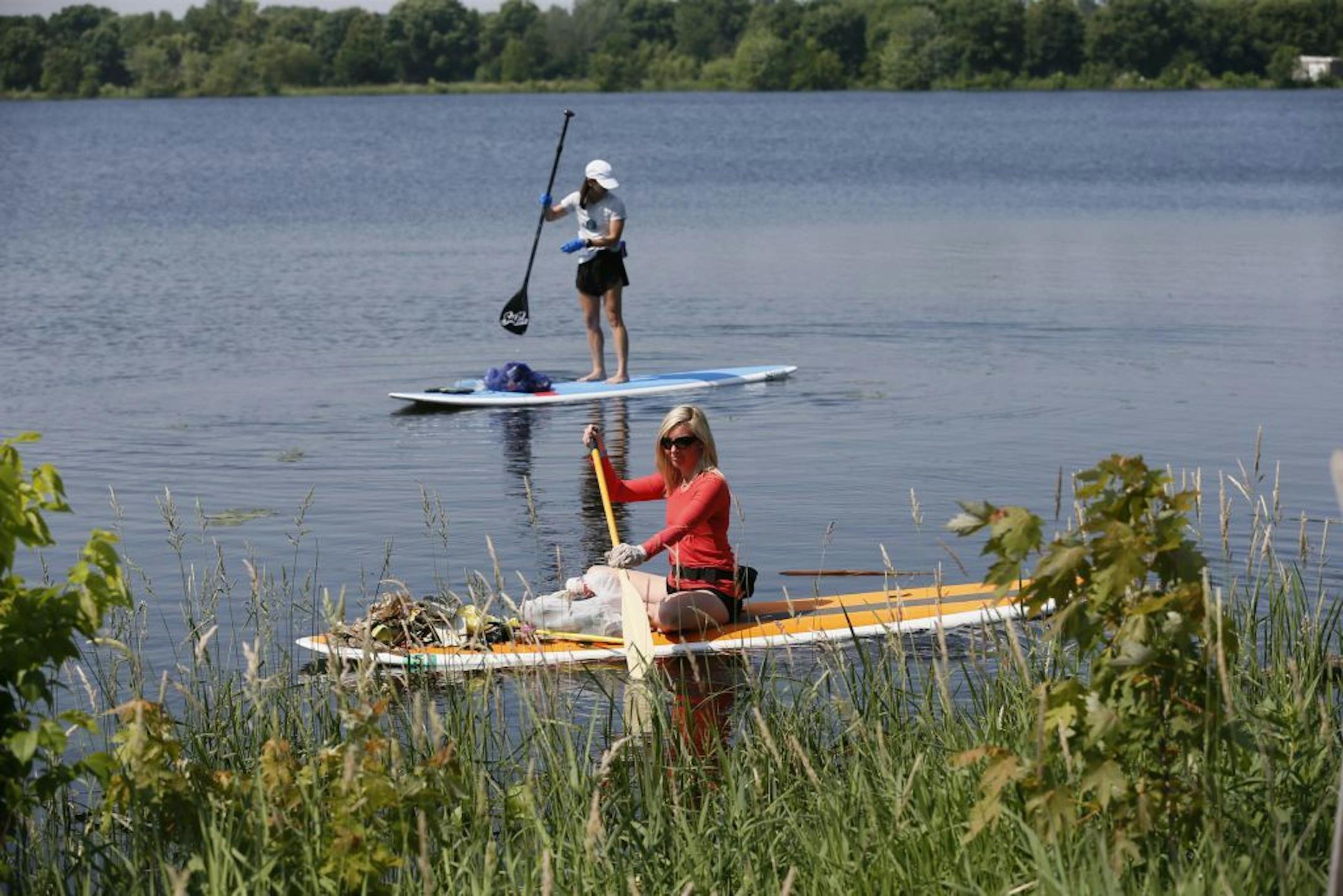 Holly Evans owner of Wai Nani paddle boards, and Marie Hilligoss joined More than 1200 volunteers who removed trash from Lake Hiawatha during a clean up of the Minnehaha Creek Watershed District and nearby lakes Sunday June 30, 2013 in Minneapolis, MN .