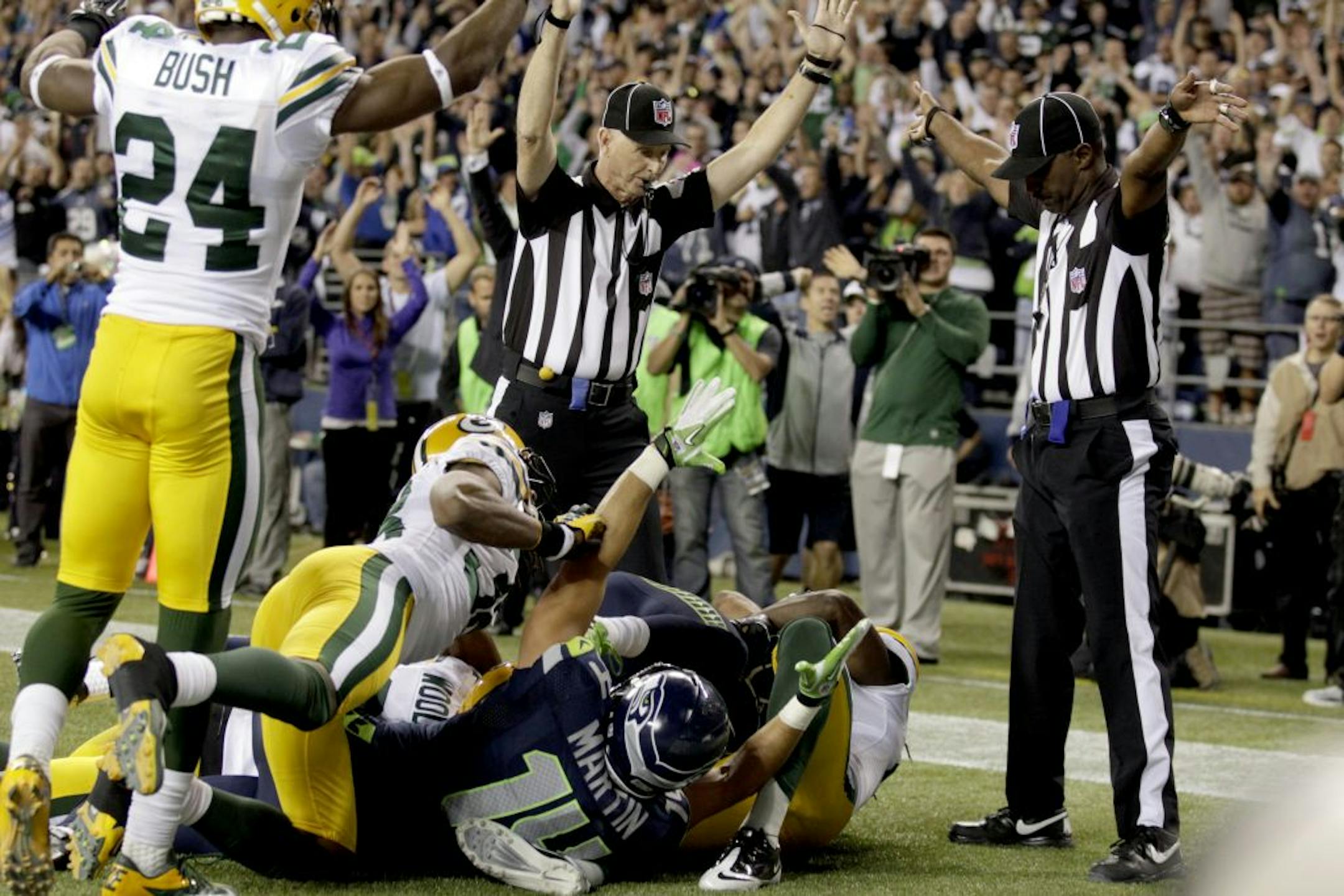 Officials signal a touchdown by Seattle Seahawks wide receiver Golden Tate, obscured, on the last play of an NFL football game against the Green Bay Packers, Monday, Sept. 24, 2012, in Seattle. The Seahawks won 14-12.