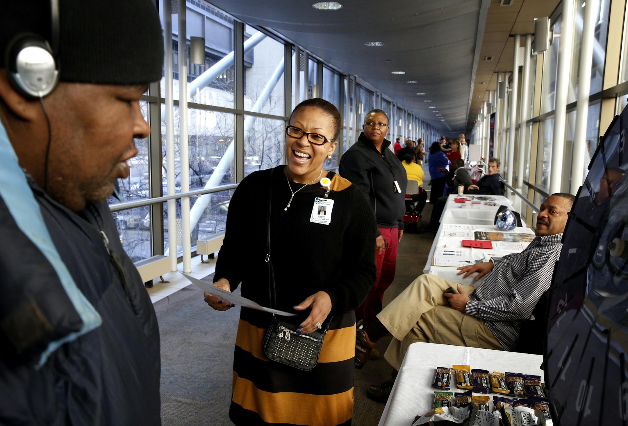 Patricia Settles, center, a senior community health worker at HCMC, plays a quiz game with Andrew Minor, left, of Minneapolis for prizes during a World AIDS Day resource fair at Hennepin County Medical Center in Minneapolis on Monday, December 1, 2014. The quiz tested people's knowledge of HIV/AIDS and the Positive Care Center for HIV/AIDS patients at HCMC. ] LEILA NAVIDI leila.navidi@startribune.com /