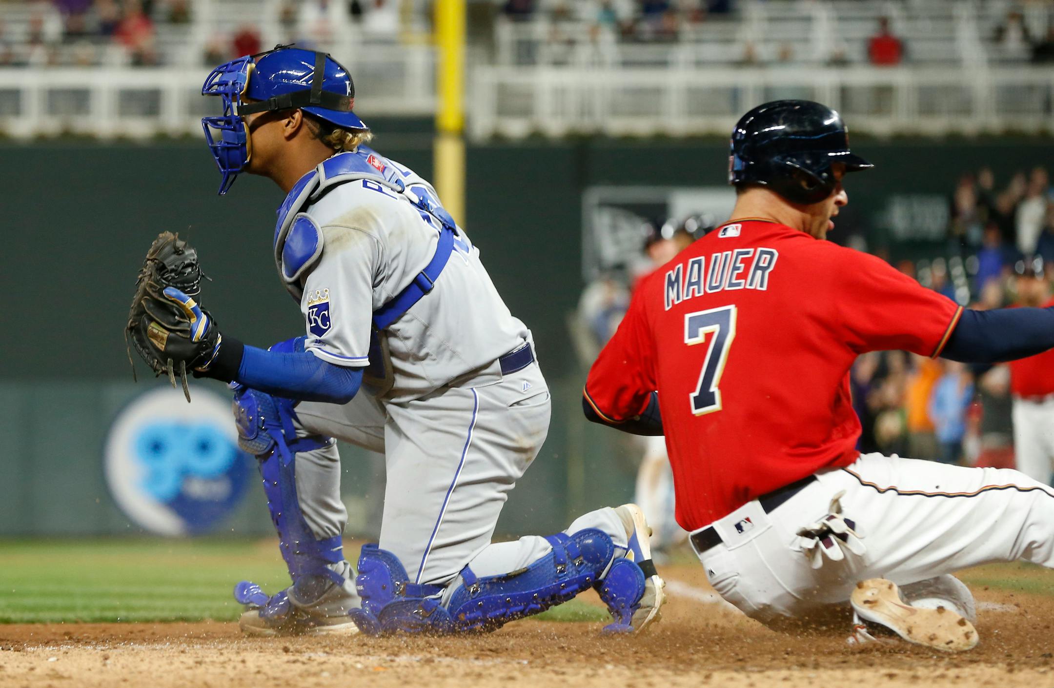 Minnesota Twins' Joe Mauer, right, scores the winning run past Kansas City Royals catcher Salvador Perez on Jorge Polanco's sacrifice fly in the 10th inning of a baseball game Friday, May 19, 2017, in Minneapolis. The Twins won 4-3. (AP Photo/Jim Mone)
