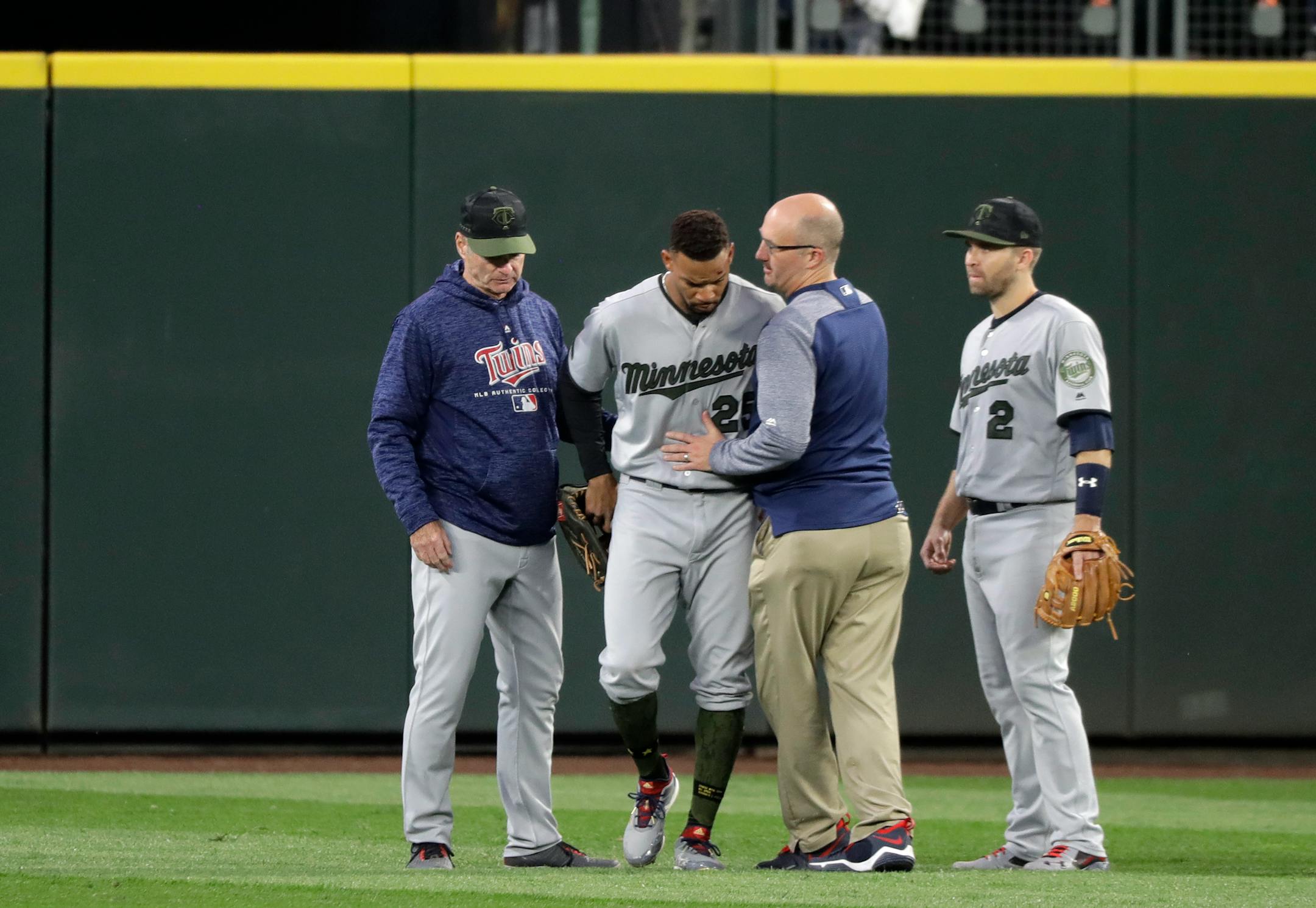 Minnesota Twins center fielder Byron Buxton, second from left, is attended to by head trainer Tony Leo, second from right, after he crashed into the wall while trying to catch a two-run home run hit by Seattle Mariners' Nelson Cruz during the sixth inning of a baseball game, Saturday, May 26, 2018, in Seattle. (AP Photo/Ted S. Warren)