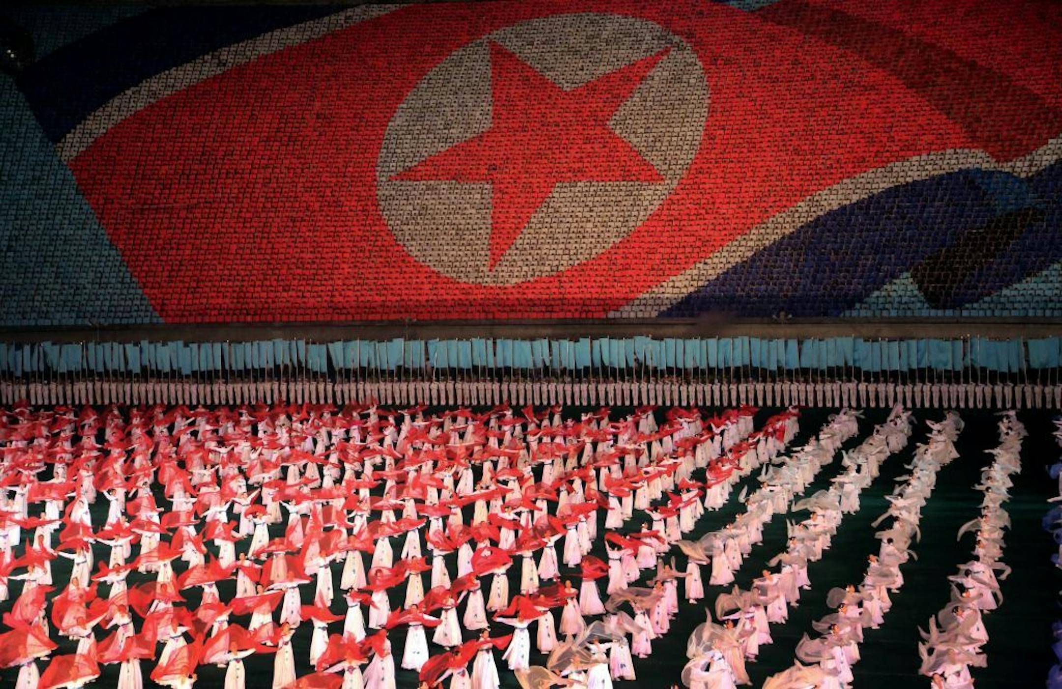 North Korean women dance in front of a display of their country's national flag on Monday, July 22, 2013 in Pyongyang, North Korea. North Korea has revealed a new rendition of the "Arirang" mass games, the song-and-dance ensemble. This year�s performance was timed to debut for the 60th anniversary Saturday of the end of the Korean War, and features new scenes focusing on leader Kim Jong Un�s directives.