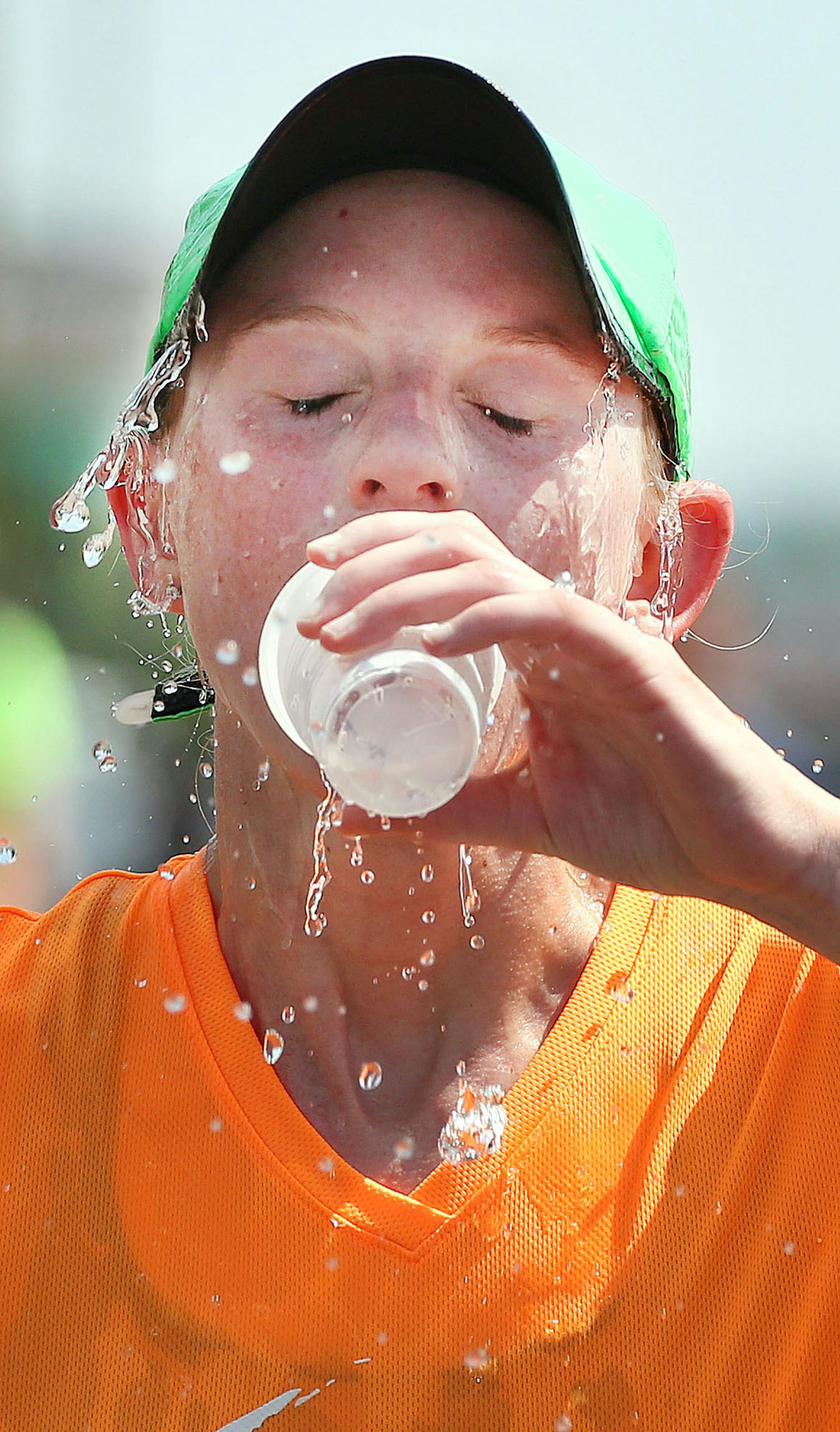 t6.18.16 Bob King -- kingRACE0619c35 -- Trying to keep cool after getting to the top of Lemon Drop Hill, Melissa Flucke of Green Bay half-splashes and half-drinks a cup of cold water she grabbed from a volunteer in Grandmas Marathon. Bob King / rking@duluthnews.com