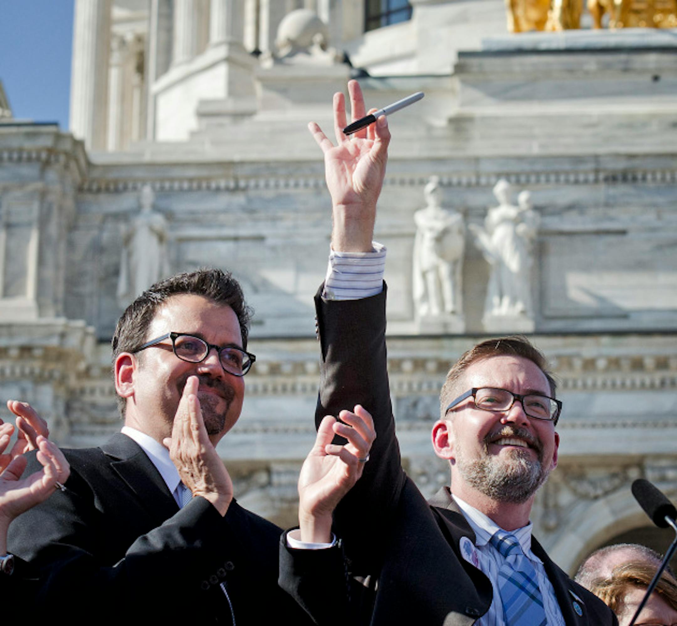 Sen Scott Dibble held up a pen used to sign the marrige bill from Mark Dayton.  On the left is husband Richard Leyva. Tuesday, May 14, 2013    ]   GLEN STUBBE * gstubbe@startribune.com