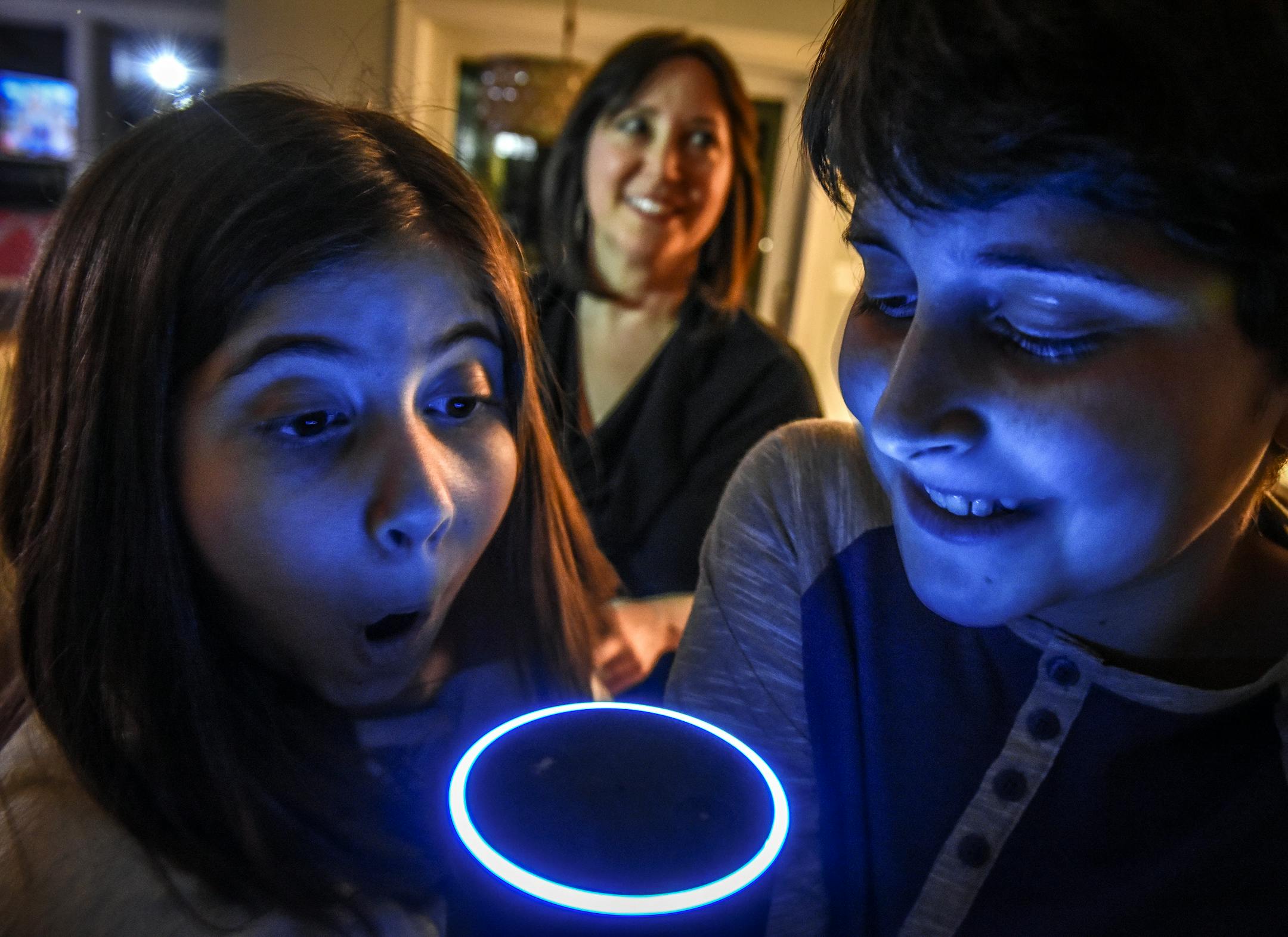 Asher Labovich, 13, and his 10-year-old brother, Emerson, left, mess around with the family's Alexa, an Amazon Echo voice assistant, while their mom, Laura Labovich, watches in Bethesda, Md.