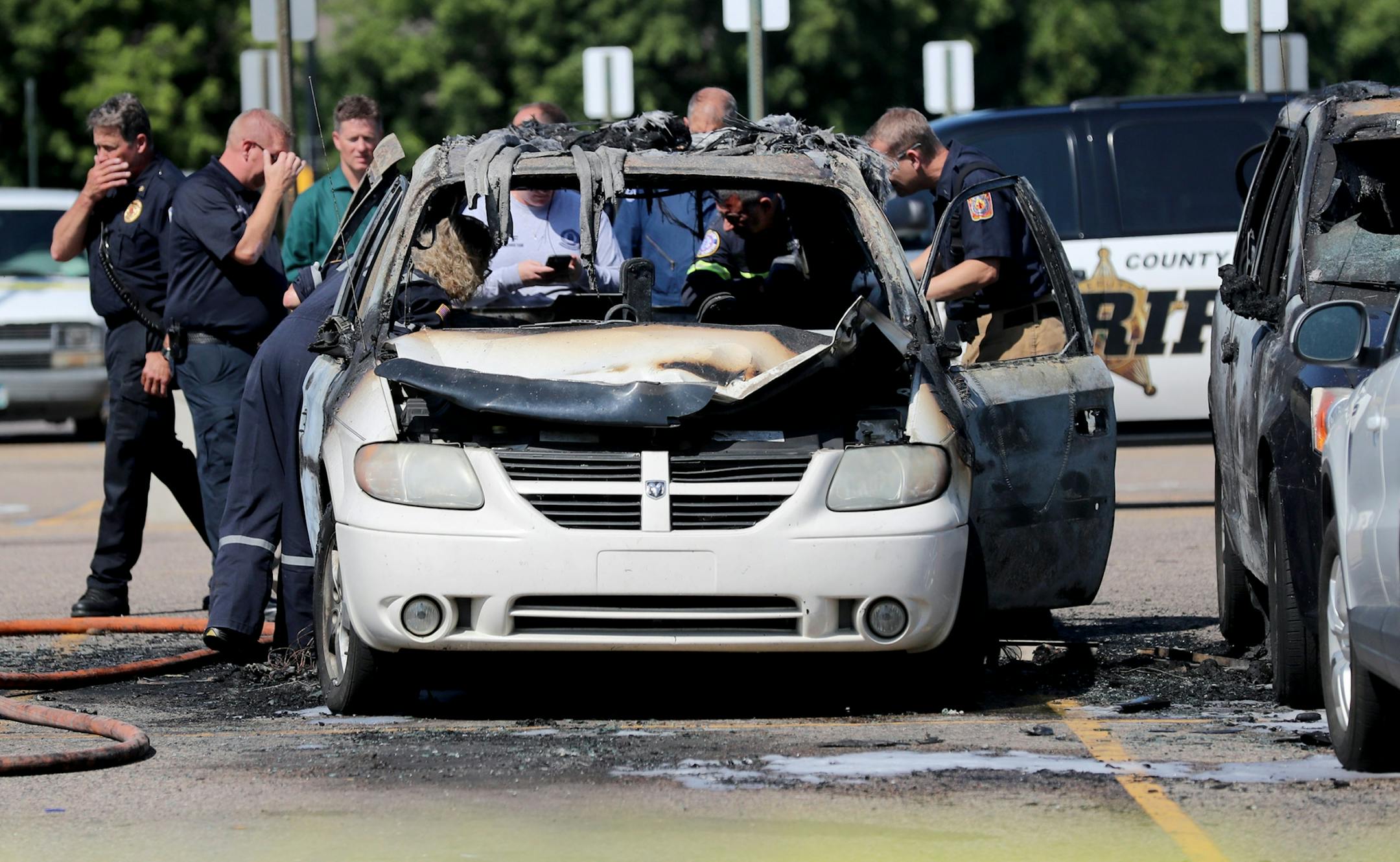 A car fire at a Fridley Walmart engulfed three vehicles and left two young passengers injured in a taxi van parked next to the vehicle where the fire originated Tuesday, Aug. 6, 2019, in Fridley, MN. Here, police and fire investigators look over the charred remains of the vehicle where the fire ignited.