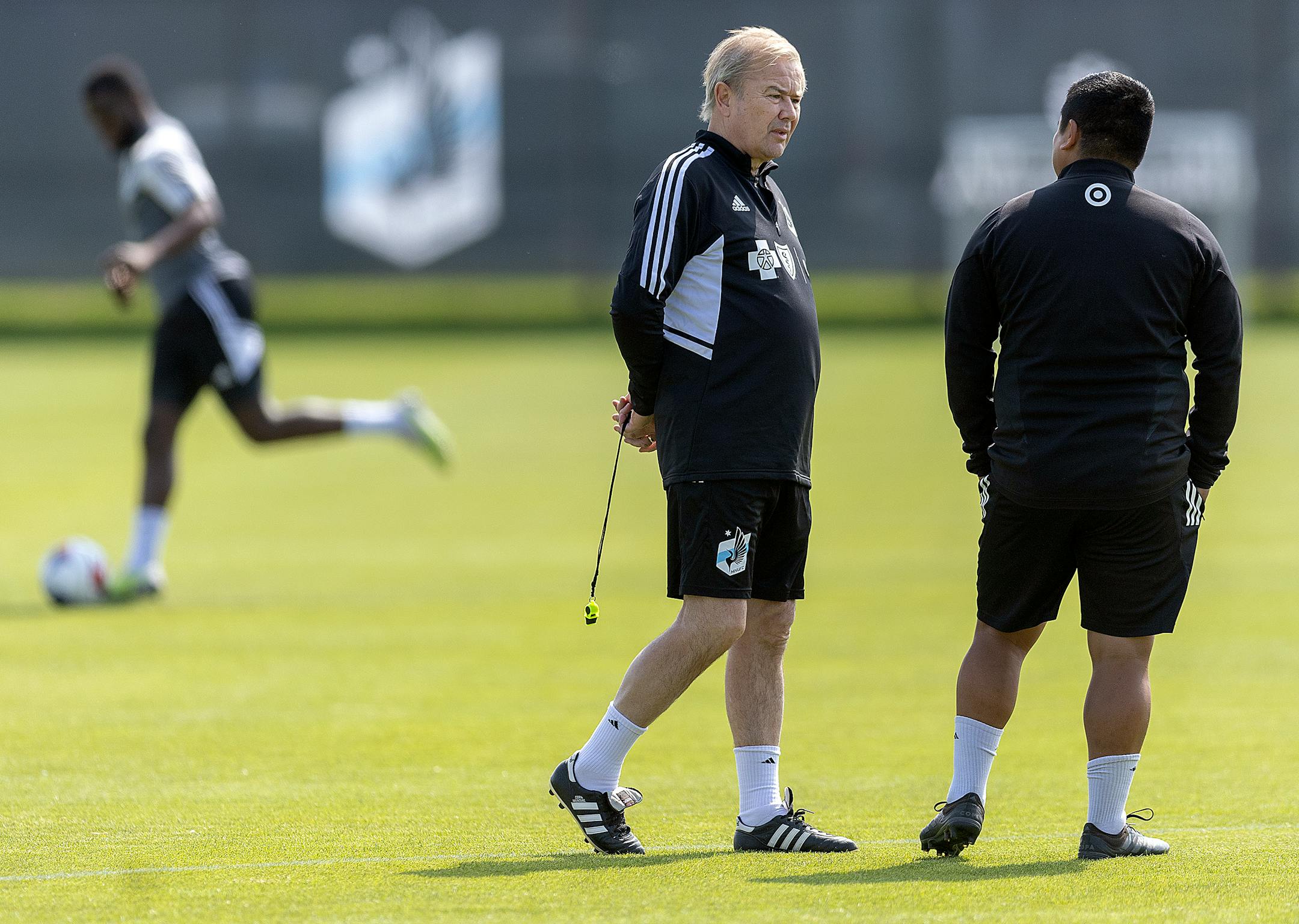 The Minnesota United Head Coach Adrian Heath takes to the field as players warm up before a brief practice.