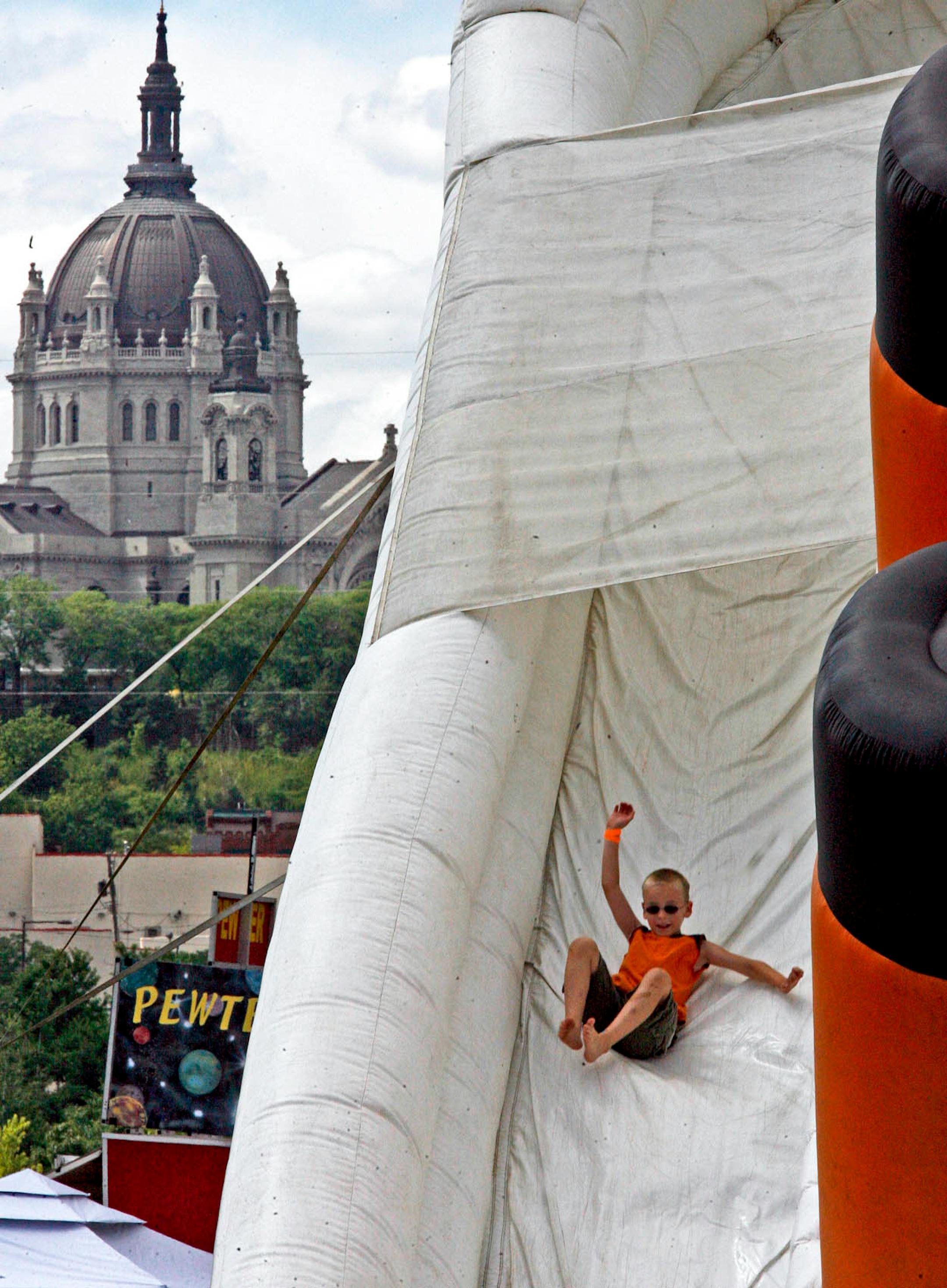 Some of the fun on the first day of Taste of Minnesota festivities included a ride down the 32-foot inflatable "Titanic" slide, which appears small compared with the St. Paul Cathedral in the background. The free festival is being held on Harriet Island through Sunday.