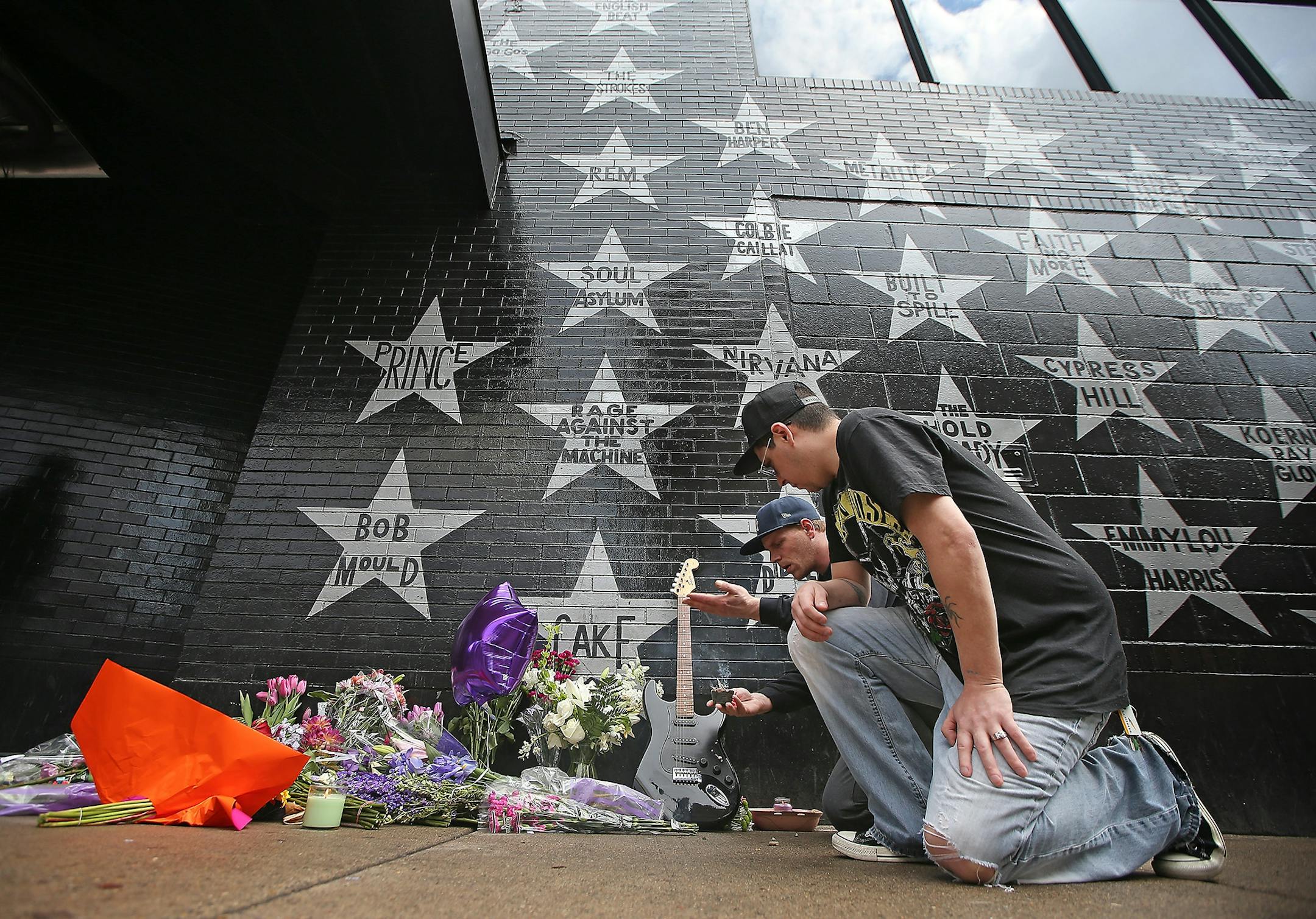 Christopher LaCroix, cq, right, left a guitar as someone burned sage near the flowers beneath Prince's star at First Avenue after news of Prince's death was made, Thursday, April 21, 2016 in Minneapolis, MN.