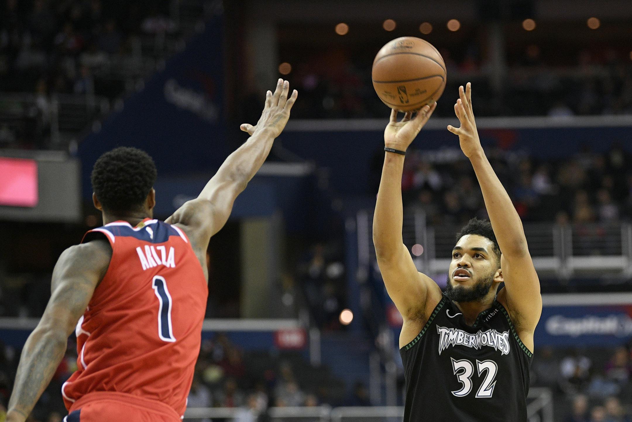 Minnesota Timberwolves center Karl-Anthony Towns (32) shoots against Washington Wizards forward Trevor Ariza (1) during the first half of an NBA basketball game, Sunday, March 3, 2019, in Washington. (AP Photo/Nick Wass)