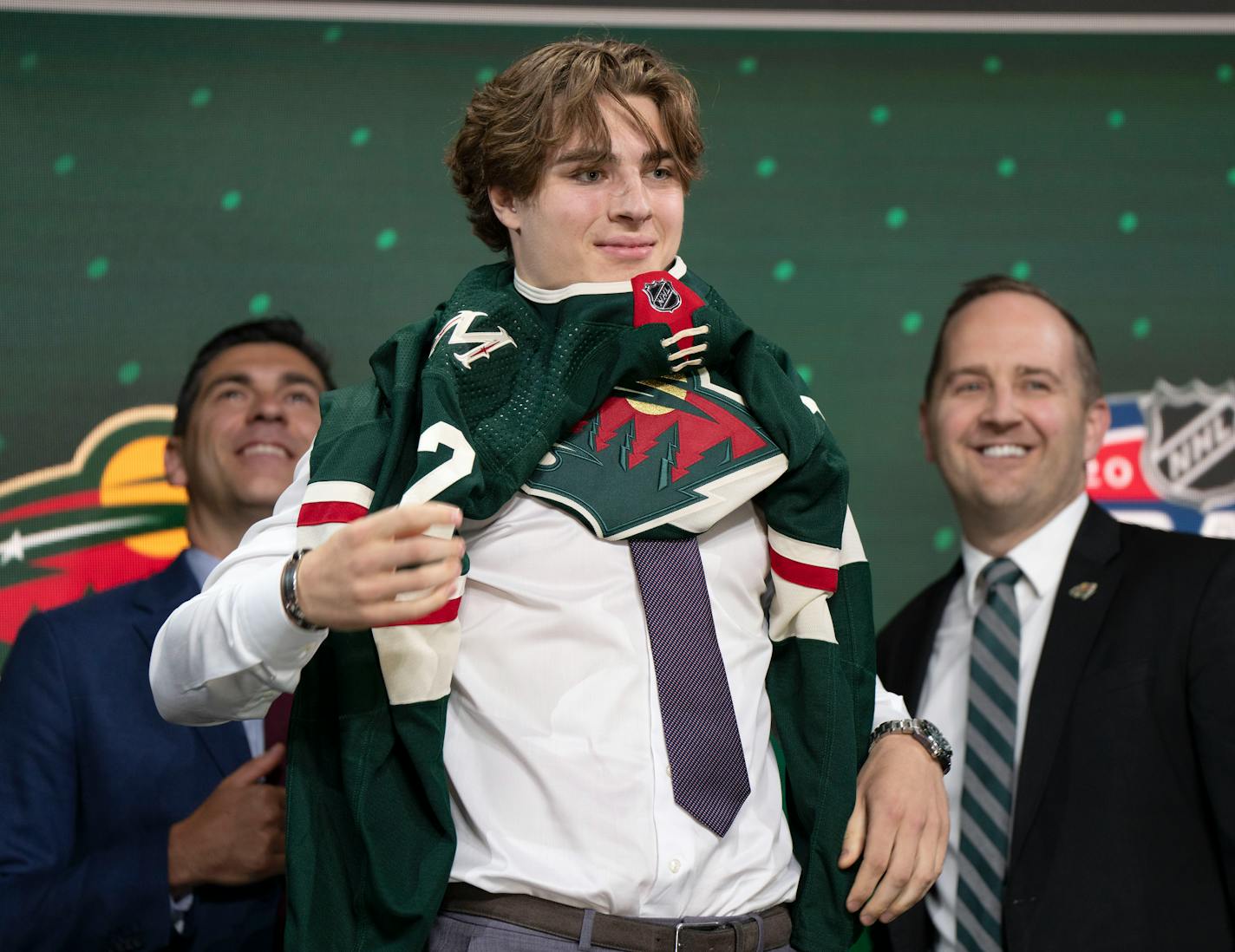 The Minnesota Wild's 19th pick, center, Liam Ohgren, puts on his jersey during the first round of the NHL hockey draft Thursday, July 7, 2022 in Montreal. (Ryan Remiorz/The Canadian Press via AP)