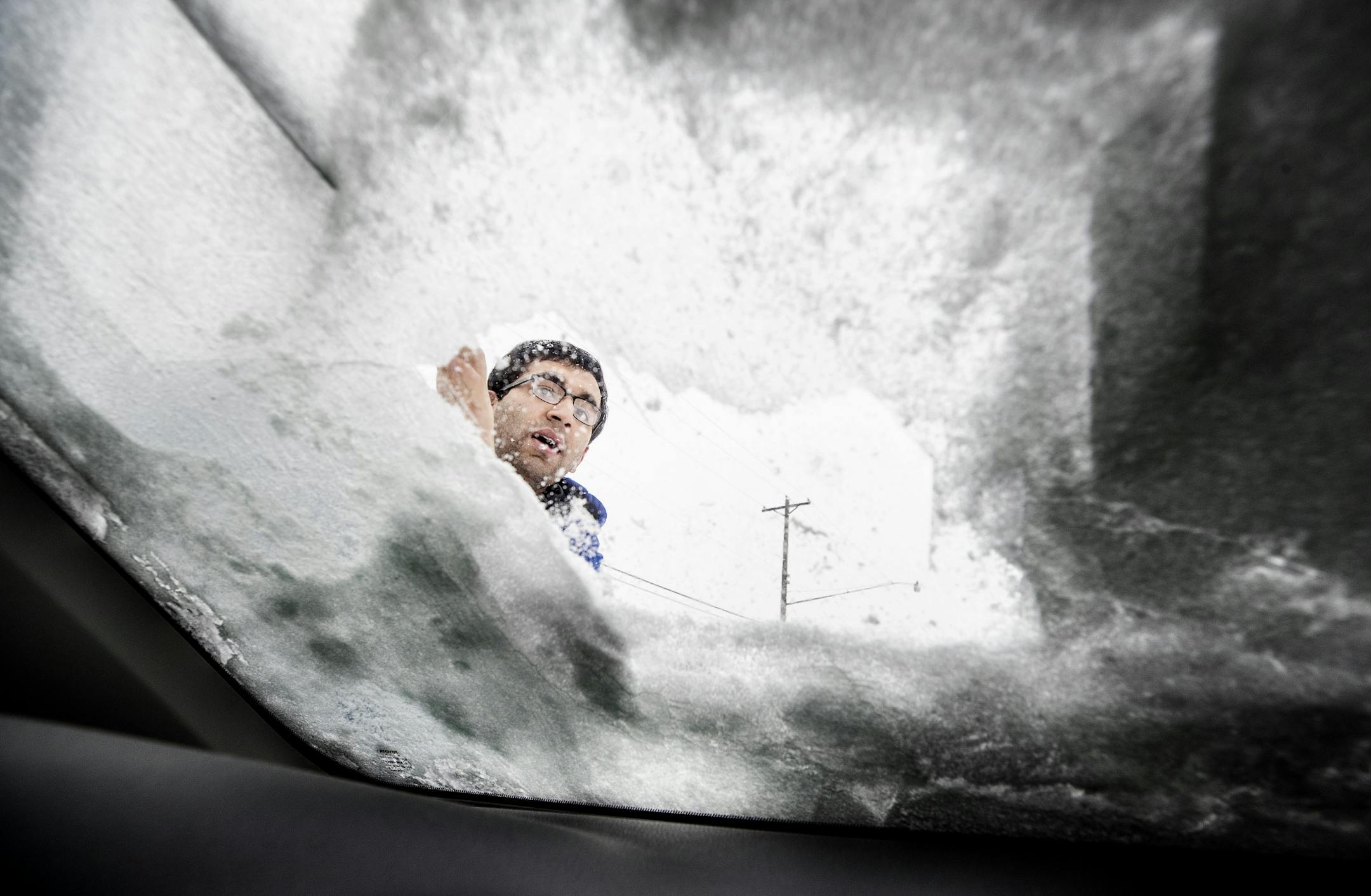 Manik Tandon of St. Paul cleaned ice and snow off of his windshield during a snow storm on Thursday.