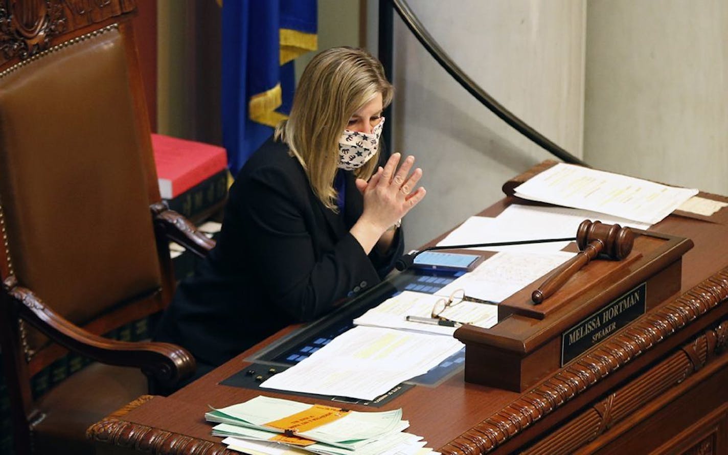 Minnesota House Speaker Melissa Hortman wears a face mask at her desk as lawmakers met, Tuesday, April 7, 2020, in St. Paul, Minn., to pass a bill to assure that first responders and medical workers will qualify for workers compensation if they get sick with COVID-19 and won't have to prove they contracted the disease on the job. The new coronavirus causes mild or moderate symptoms for most people, but for some, especially older adults and people with existing health problems, it can cause more