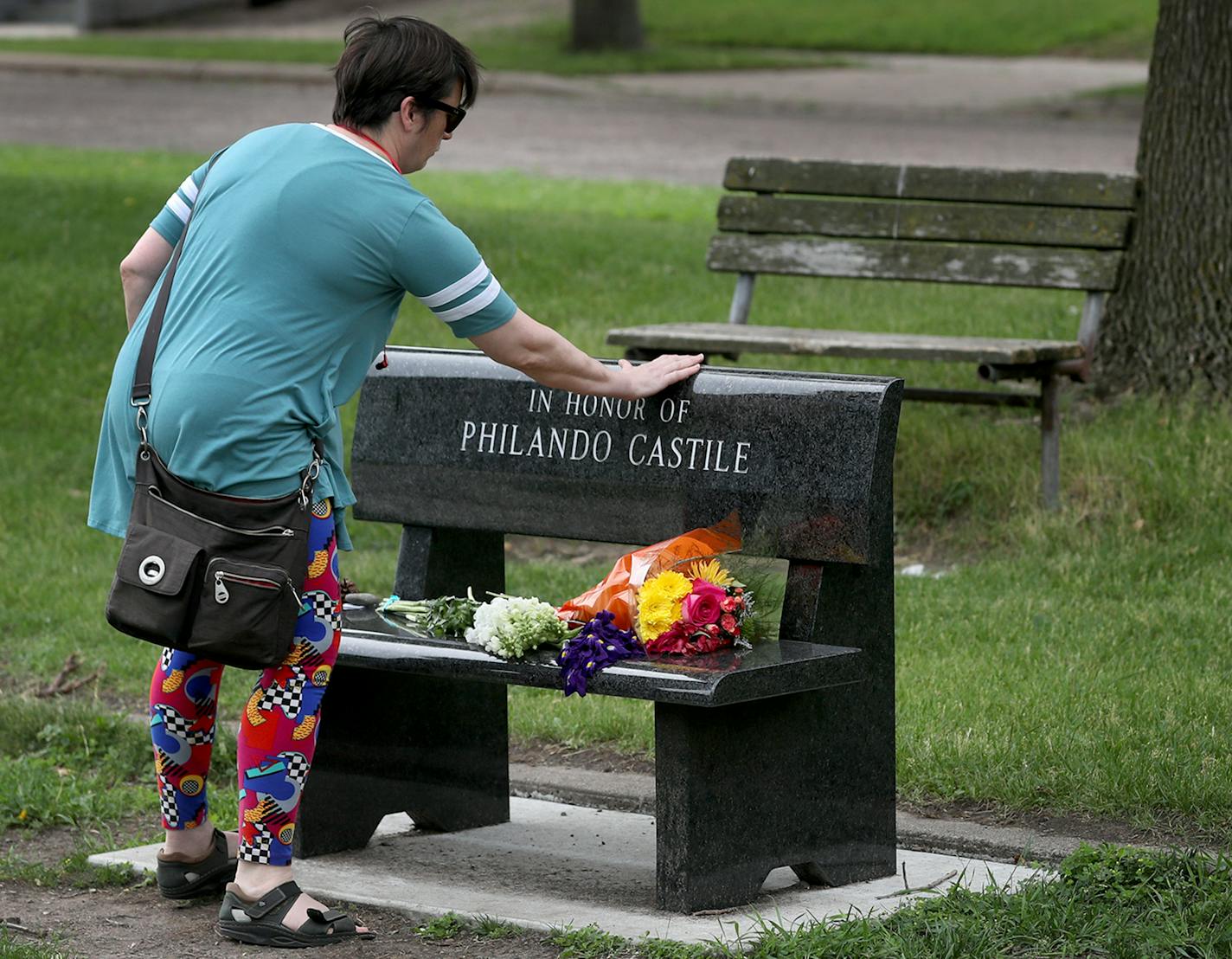 Amy Brisbane of St. Paul touches a Memorial bench to Philando Castile after leaving a message and a rock on it, outside J.J. Hill Montessori Magnet School, where Castile worked as a nutrition services supervisor and was seen Saturday, June 17, 2017. Brisbane, who has a son who is African-American, said she is shocked "beyond belief," by the acquittal of Yanez because she said she didn't believe something like Castile's killing and the acquittal of Yanez could happen in the Twin Cities. Castile w