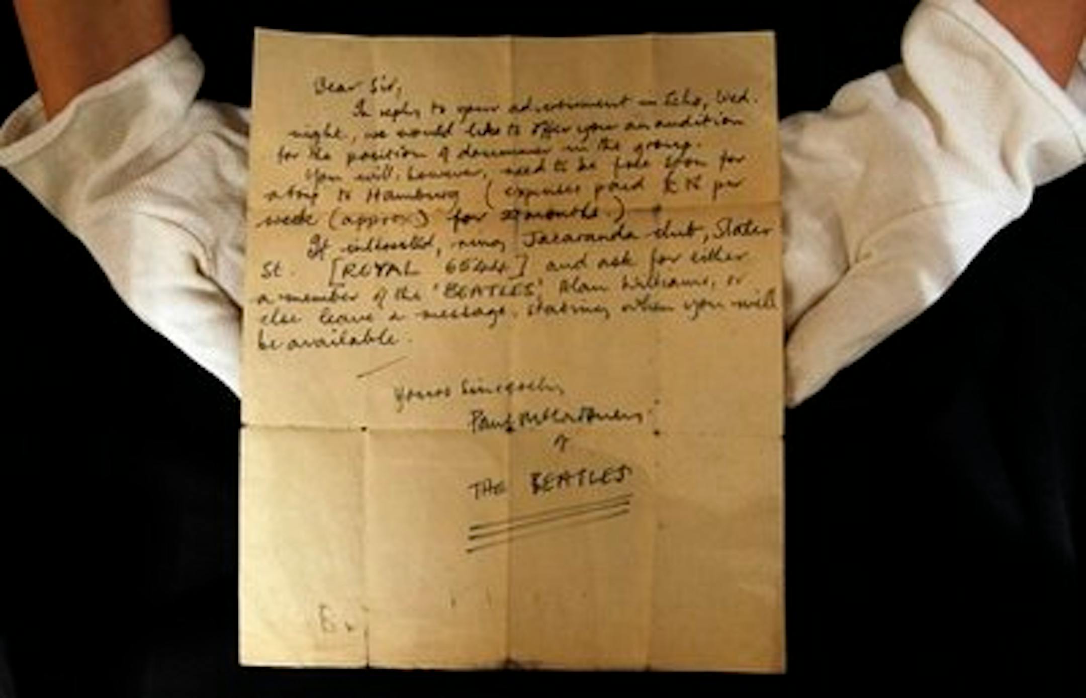 A Christie's employee displays a letter  inviting an unknown drummer to audition for The Beatles, at their auction house in London,  Monday, Oct. 17, 2011. The handwritten letter by Paul McCartney, dated 12 August 1960, inviting an unknown drummer to audition for The Beatles, was discovered folded-up inside a book, by an anonymous collector at a car boot sale in Bootle, Liverpool, England. It is expected to sell at auction for 7,000-9,000 pounds (11,050- 14,200 US dollars). (AP Photo/Kirsty Wigglesworth)