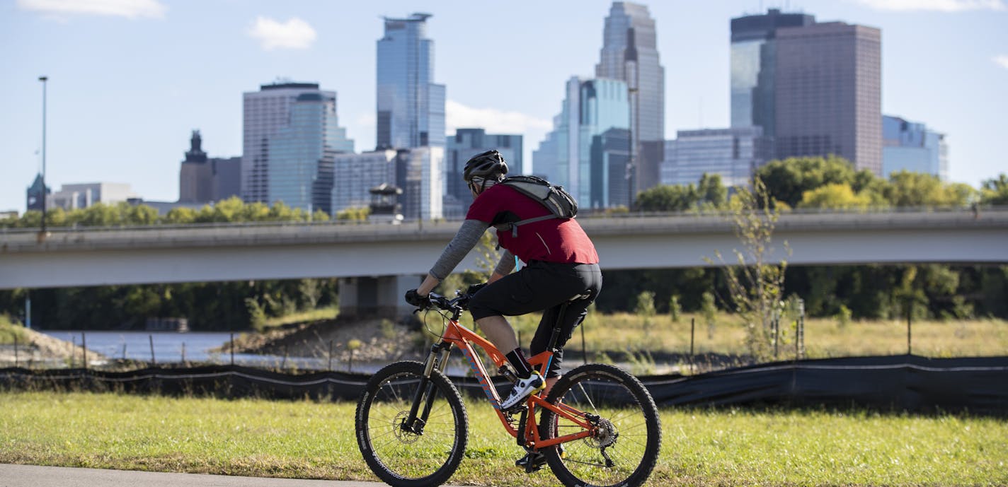 A cyclist rode past on a path in the future home of a park next to the Graco factory with a view of downtown. The Minneapolis Park Board says it has reached a settlement with Graco Minnesota Inc. over an easement on riverside property owned by Graco. Photographed in Minneapolis, Minn., on Friday, September 28, 2018. ] RENEE JONES SCHNEIDER &#x2022; renee.jones@startribune.com