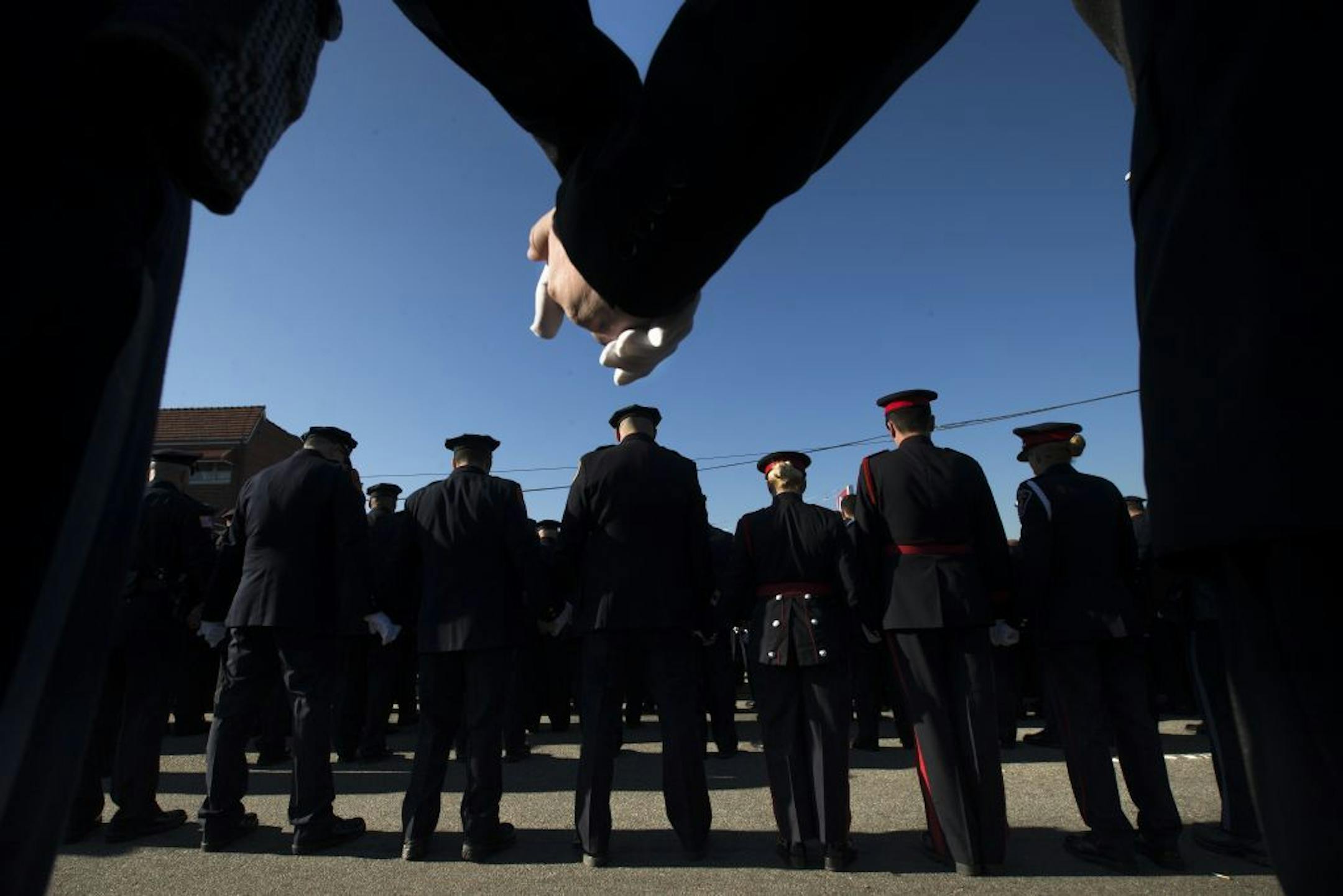 FILE- In this Dec. 27, 2014, file photo, police officers hold hands in prayer during the funeral service of New York City police officer Rafael Ramos in the Glendale section of Queens in New York. Their attacker, Ismaaiyl Brinsley, had referenced in online posts the high-profile killings by white police officers of unarmed black men, specifically Michael Brown in Ferguson, Missouri, and Eric Garner in the New York borough of Staten Island.