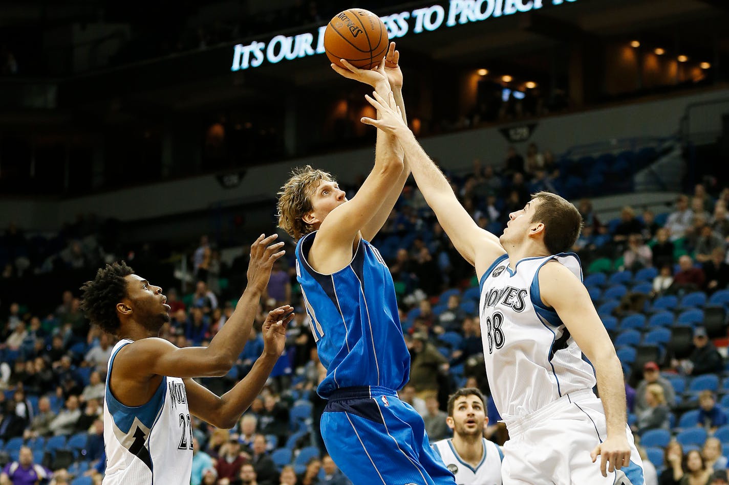 Dallas Mavericks forward Dirk Nowitzki (41) shoots the ball against Minnesota Timberwolves forwards Andrew Wiggins (22) and Nemanja Bjelica (88) in the second half of an NBA basketball game, Sunday, Jan. 10, 2016, in Minneapolis. The Mavericks won 93-87. (AP Photo/Stacy Bengs)