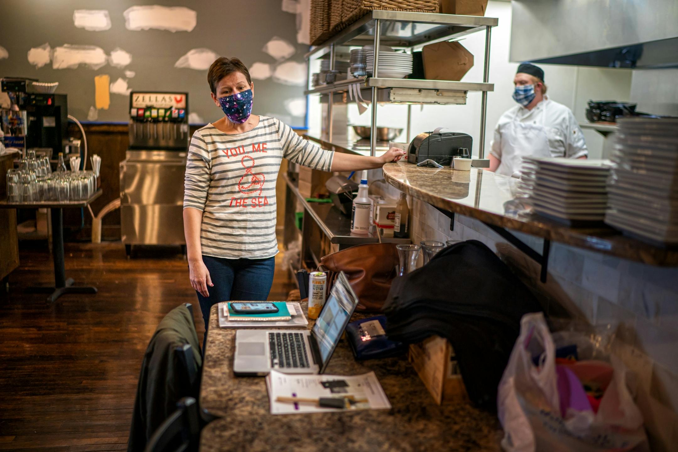 Sara Pollmann, owner of Zellas Restaurant on Main Street, Hutchinson, stood by as chef Ben Schuth prepared a carryout order. She is taking advantage of the restaurant downtime to do some remodeling. The yellow swatch in the center will replace the green wall.