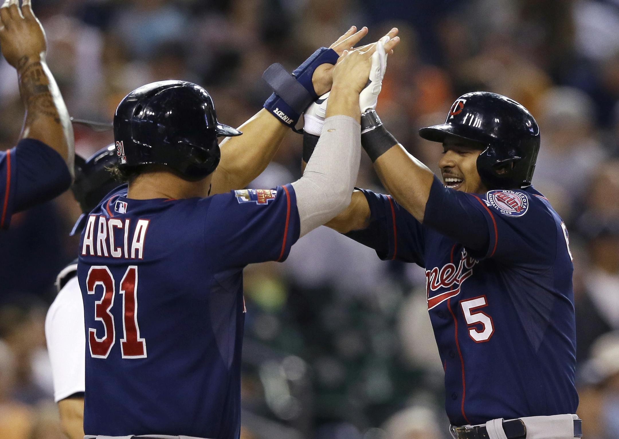 Minnesota Twins' Eduardo Escobar (5) is congratulated by teammate Oswaldo Arcia after his three-run home run during the eighth inning of a baseball game against the Detroit Tigers in Detroit, Saturday, Sept. 27, 2014. (AP Photo/Carlos Osorio)