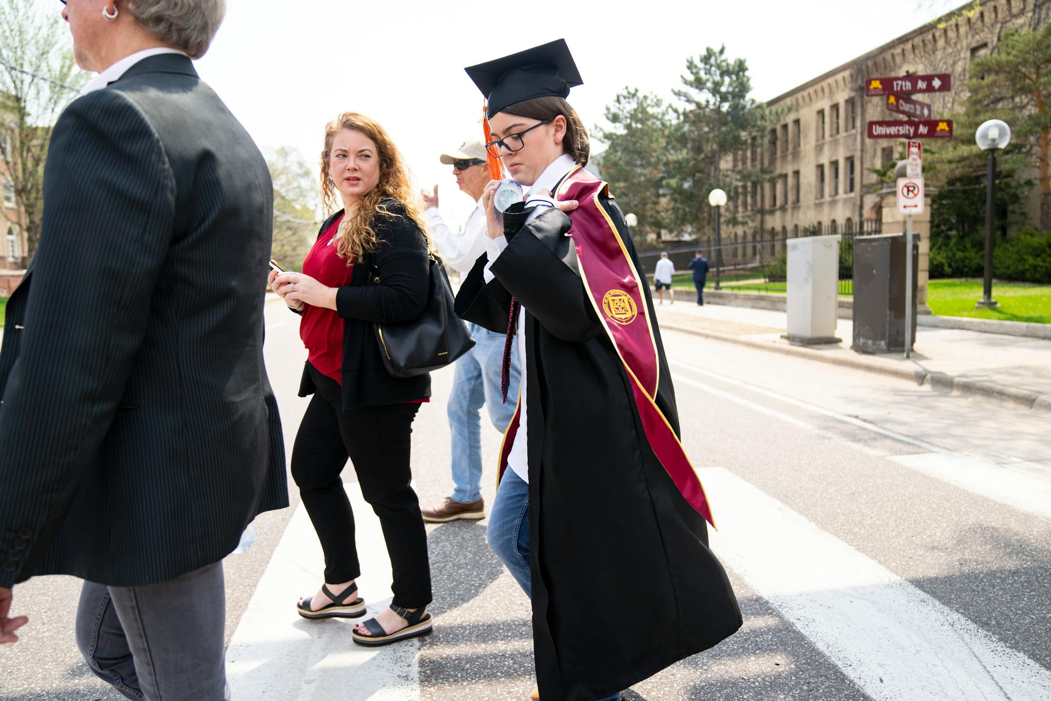 Elliott Tanner, 13, catches his stole as he walks to his graduation with his family.