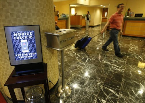 In this Oct. 14, 2014 photo, hotel guest J.D. Solomon, of Indianapolis, right, strolls out of the lobby after using the mobile check-in counter at the Marriott Marquis Times Square hotel in New York. Marriott International launched the ability to check in through its app at 330 North American hotels last year. By the end of this year, the program will be live at all 4,000 hotels worldwide.