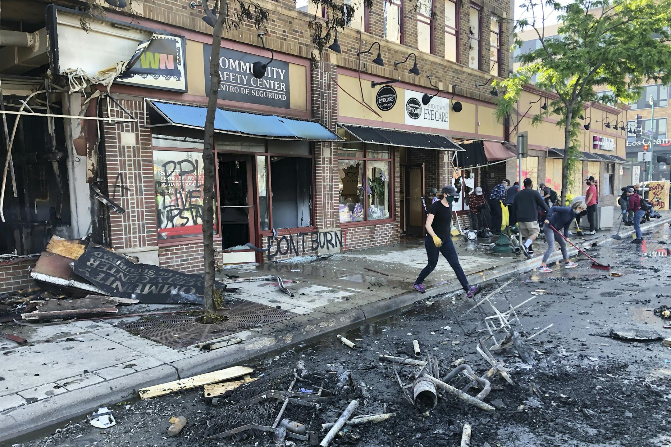 People clean up burned businesses on May 30 after a night of fires and looting following the death of George Floyd.