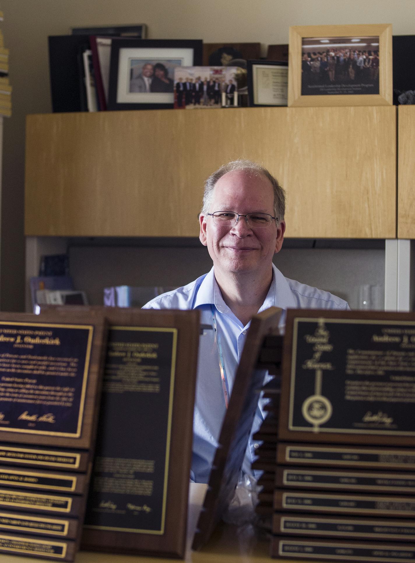 On the 3M campus, scientist Andy Ouderkirk made the optical film that extends the battery life of cell phones and laptops. He is sitting behind some of the plaques for the hundreds of patents he has helped produce. Ouderkirk will make the transition to 3M's new $150 million R&D.] Richard Tsong-Taatarii/rtsong-taatarii@startribune.com