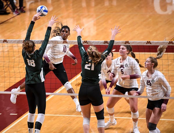 Minnesota Gophers opposite Stephanie Samedy (10) spiked the ball against Michigan State outside hitter Molly Johnson (18) and middle blocker Rebecka P