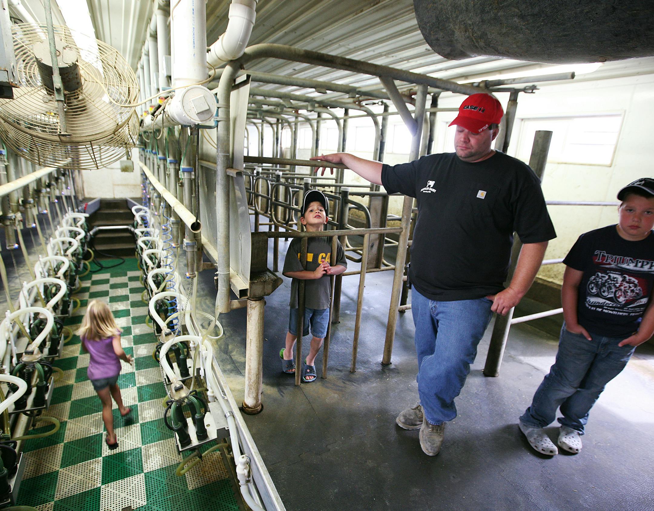 While his children, left to right, Dani, 7, Shayne, 5, and Brett, 10, play in the milking parlor, dairy farmer Harlan Poppler gets emotional as he considers the many dead cows he had to carry out of his barns over recent years at Poppler Dairy Farm in Waverly July 25, 2013. His cows were affected by stray currents from a local electric company. (Courtney Perry/Special to the Star Tribune)